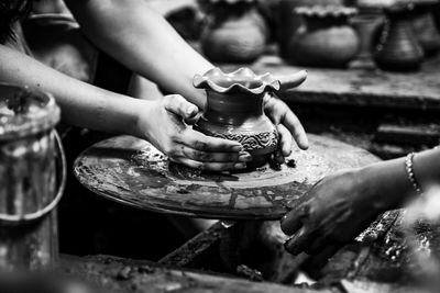 Cropped hands of people molding shape on pottery wheel