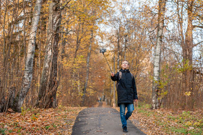 A teenage boy walks through an autumn park and shoots a video. blogger. emotional communications..