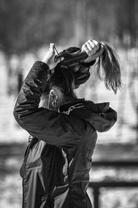 Woman tying hair while standing outdoors