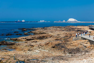 People on beach against clear blue sky