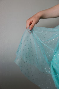 Midsection of woman holding umbrella against white wall