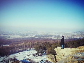 Rear view of woman standing on snow covered landscape
