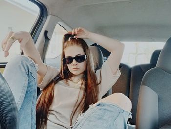 Portrait of young woman wearing sunglasses while sitting in car