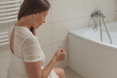 Side view of young woman sitting in bathroom