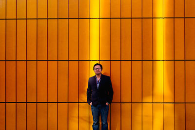 Portrait of a young man standing against yellow wall