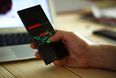 Close-up of hand using laptop on table