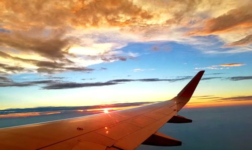 Airplane flying against sky during sunset