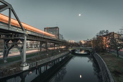 Bridge by river in city against sky at night