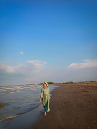 Full length of women standing on beach against sky