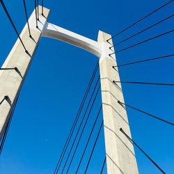 Low angle view of suspension bridge against clear blue sky