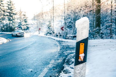 Snow covered road by trees