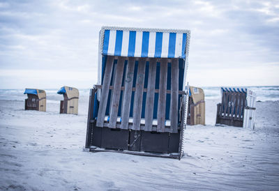 Lifeguard hut on beach against sky during winter