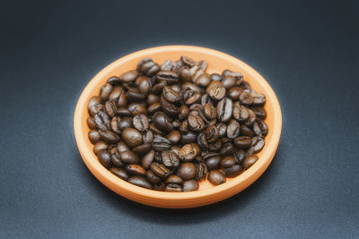 Close-up of roasted coffee beans in bowl on table
