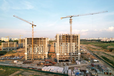 Cranes at construction site against sky