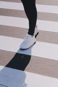 Low section of woman standing on zebra crossing