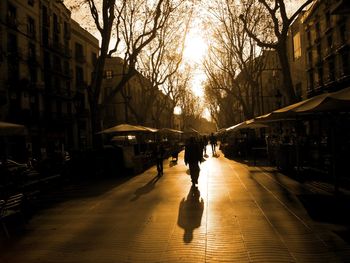 Silhouette people walking on street amidst buildings in city