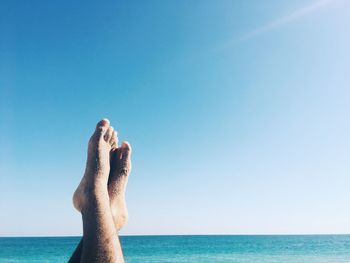 Low section of man by sea against sky