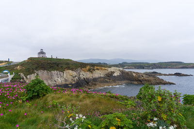 Lighthouse by sea against sky