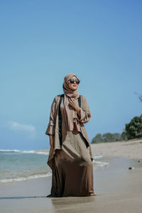 Low angle view of woman standing at beach against clear sky