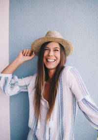 Portrait of smiling young woman against wall