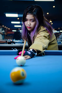 Portrait of young woman playing pool