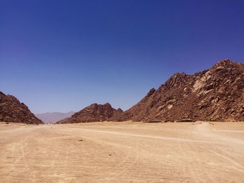 Scenic view of desert against clear blue sky