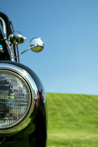 Close-up of vintage car on field against clear blue sky