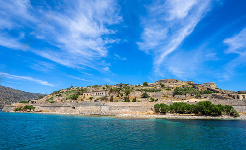 Island by sea against blue sky