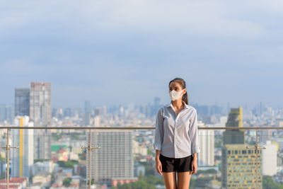 Full length of young woman standing against cityscape