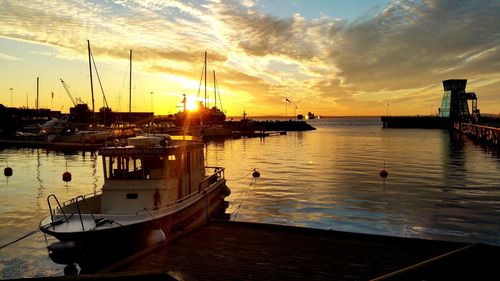 Boats moored at harbor during sunset