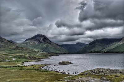 Scenic view of landscape and mountains against storm clouds