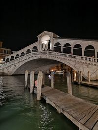 Arch bridge over canal against sky at night