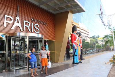 People walking on footpath by building
