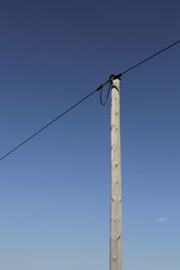 Low angle view of pole and cable against clear blue sky