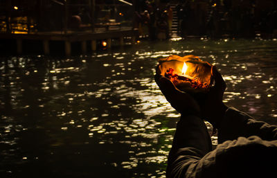 Devotee holding aarti flower pot for ganges river evening prayer at night