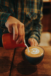 Midsection of barista preparing coffee in cafe