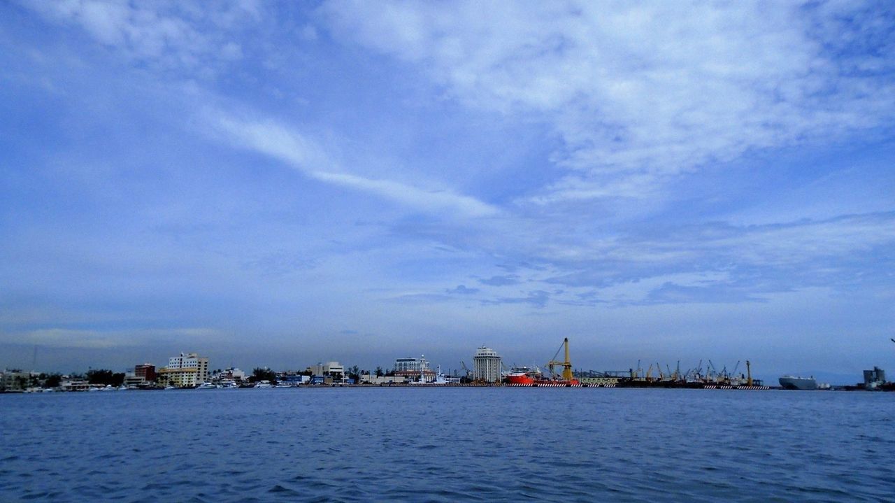 waterfront, water, sky, architecture, built structure, sea, city, cloud - sky, blue, cityscape, cloud, rippled, nature, mid distance, urban skyline, outdoors, scenics, cloudy, no people, tranquility, day, tranquil scene, beauty in nature, ocean, development