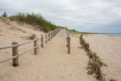 Wooden posts on beach against sky