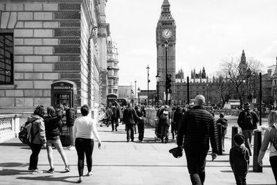 Rear view of people walking on street by big ben against clear sky