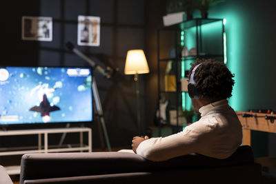 Rear view of woman using mobile phone while sitting at home