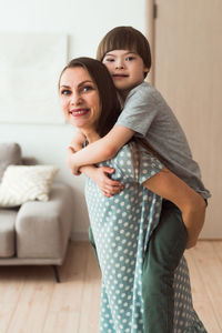 Loving mother holding piggy back boy with down syndrome