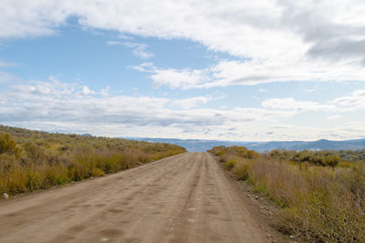 Road amidst field against sky