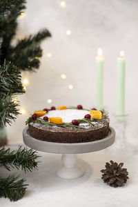 The christmas cake on cake stand with candles and christmas tree. grey background. vertical frame.