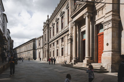 Rear view of people in front of historic building