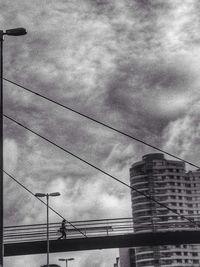 Low angle view of power lines against cloudy sky