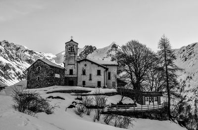 Houses by trees on snow covered house against sky