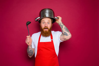 Portrait of young man standing against red background