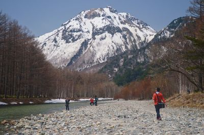 Rear view of people walking on mountain against sky