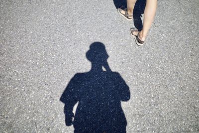 Shadow and low section of people walking on road