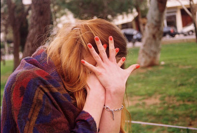 Close-up of woman with hand on tree